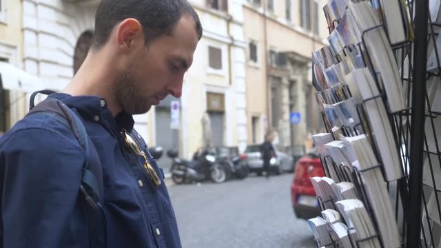 Young Male Tourist Choosing Postcards.