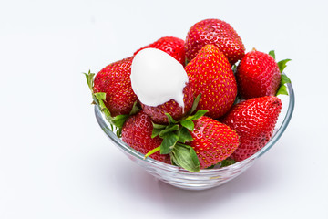 The white cream on the one strawberry in the bowl full of strawberries