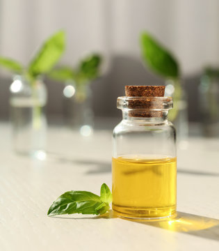 Bottle of essential basil oil on table against blurred background. Space for text