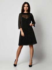 Young beautiful woman posing in new black fashion winter dress full body on a white 