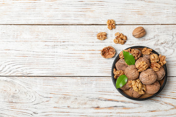 Plate with walnuts and space for text on wooden background, top view