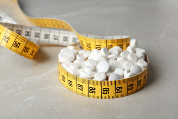 Weight loss pills with measuring tape on table
