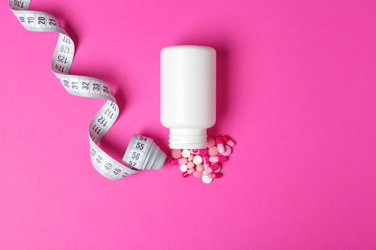 Weight loss pills, bottle and measuring tape on color background, flat lay