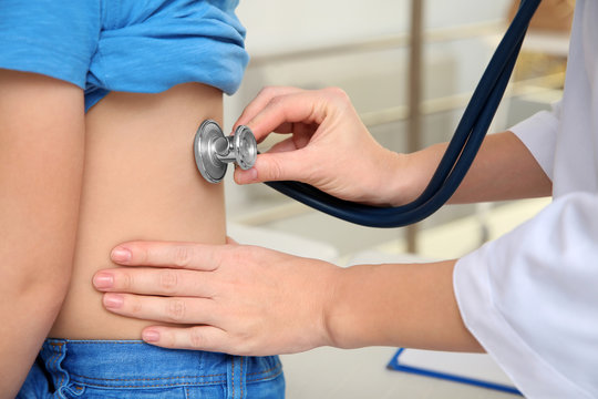 Children's doctor examining patient with stethoscope in hospital, closeup