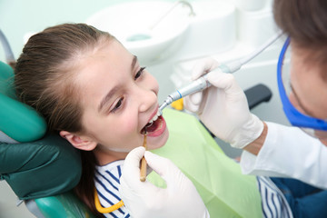 Professional dentist working with little patient in modern clinic