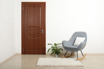 Modern room interior with brown door and rocking chair. Space for text