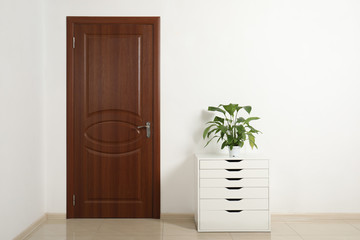 Modern room interior with small cabinet and closed door. Space for text