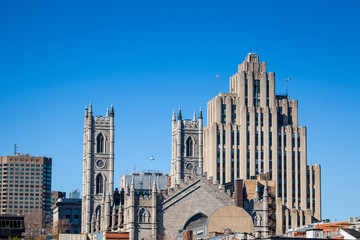 Skyline of the Old Montreal, with the Notre Dame Basilica in front, and a vintage stone Skyscraper in the background. The basilica is the cathedral of Montreal, Quebec, Canada, & a touristic landmark
