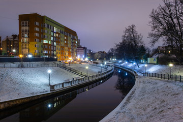 romantic night snow-covered park with lanterns and a river