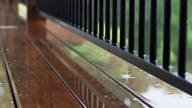 Wood deck walkway with barrier fence around a house in the rain Close up