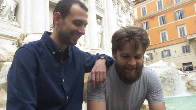 Two Good Friends Talking And Laughing In Front Of The Trevi Fountain.