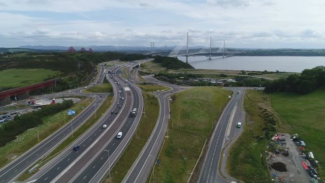 Drone shot flying over the M90 motorway towards the Queensferry Crossing cable-stayed bridge near Edinburgh in Scotland