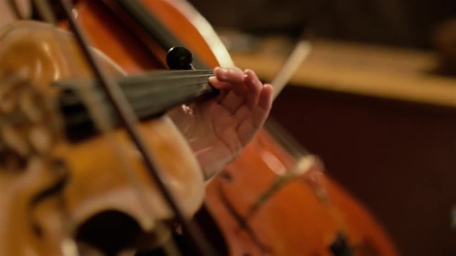 Viola playing. View of the bow and the left hand. Cello playing in the background. Shallow depth of field. Slow motion