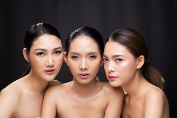 Group Three Beautiful Asian Long straight black hair tan skin women portrait in open naked shoulder, fashion make up, studio lighting dark background Empty copy space, concept bath skincare product