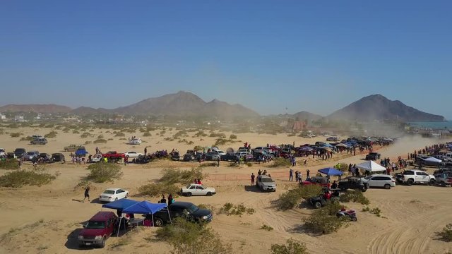 Aerial shot of the San Felipe 250 race. Trophy Truck races from right to left at hight speed, you can see mountains in the background.