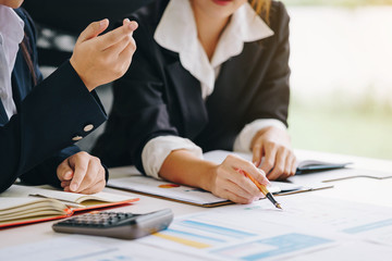 Businesswoman holding a pen pointing the graph and partnership to analyze the marketing plan with calculator. Meeting brainstorming and discussing project. Teamwork concept.