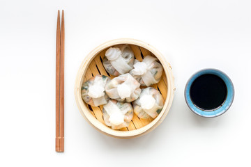 Chinese food set with dim sum, sticks and tea on white background top view