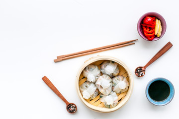 Dinner in Chinese restaurant with dim sum, sticks and tea on white background top view space for...