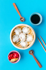 Dim sums with red pepper and vegetables with sticks and black tea in Chinese restaurant on blue background top view