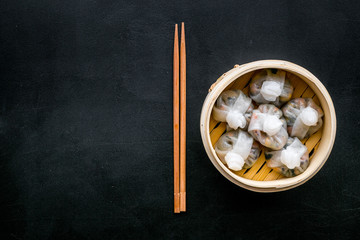 Dinner in Chinese restaurant with dim sum, sticks on black background top view space for text