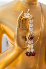 Naklejka premium Close up Hand of The Buddha statue gold color hold flower garland in temple at thailand