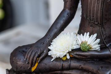 Close up Hand of The Buddha statue dark color with flower in temple at thailand