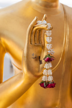 Close up Hand of The Buddha statue gold color hold flower garland in temple at thailand