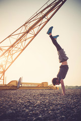 Fototapeta na wymiar Young man practicing handstand at sunset