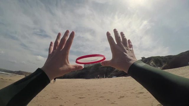 First-person POV shot of a guy catching a frisbee at the beach