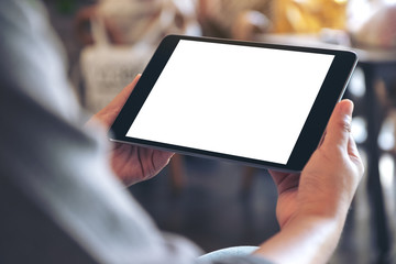 Mockup image of a woman holding black tablet pc with blank white screen horizontally while sitting in cafe