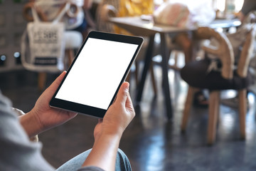 Mockup image of a woman holding black tablet pc with blank white screen while sitting in cafe