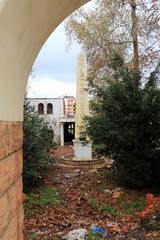 Abandoned park with a pillar with Egyptian hieroglyphs and a ruined building in the background