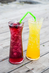 Juice mix berry, mango and passion fruit drink in tall glass with straw green color on wooden terrace