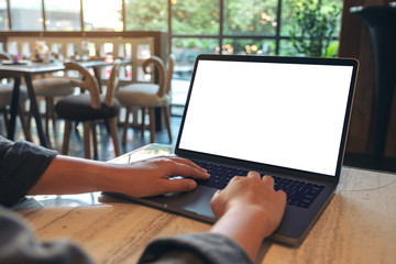 Mockup image of hands using and typing on laptop with blank white desktop screen while sitting in cafe