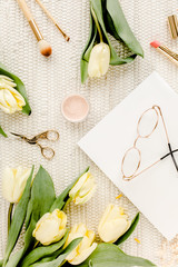 Fototapeta na wymiar Female workspace with yellow tulip flowers, women's golden accessories, diary, glasses on white background. Flat lay. Top view feminine background.