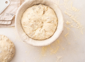 Baking bread. Dough in proofing basket on table with flour, sunflower seeds. Top view.