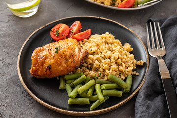 Grilled chicken thighs with bulgur, asparagus beans and tomatoes. Delicious lunch. Copy space.