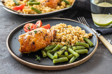 Grilled chicken thighs with bulgur, asparagus beans and tomatoes. Delicious lunch. Copy space.