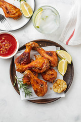 Chicken legs with sauce, rosemary and lime on a white background. Copy space. Top view.