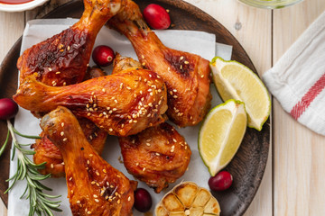 Tasty appetizing baked chicken legs served with spices, rosemary and cranberries on wooden background table. Christmas dish. Copy space.