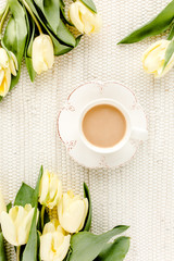 Yellow tulip flowers and cup of coffee. Flat lay, top view.