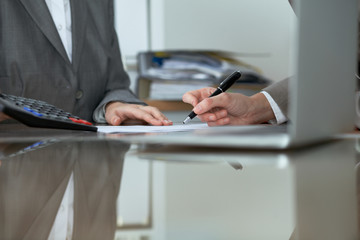 Two female accountants checking financial statement or counting by calculator income for tax form, hands close-up. Internal Revenue Service inspector checking financial document. Planning budget and