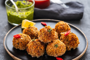 Homemade meatballs with thyme and green sauce on a black plate. Copy space.