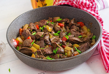 Fried chicken liver with apples and paprika in pan.