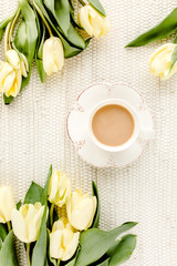 Fototapeta na wymiar Yellow tulip flowers and cup of coffee. Flat lay, top view.