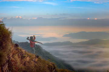 Fototapeta premium scenery view of the peak top of mountain with flowing of mist and fog under neath, photographer treking hiking the forest along mountain