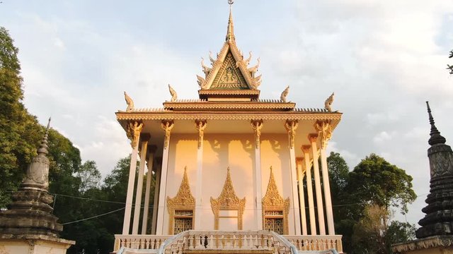 Aerial drone view ascend Khmer Buddhist temple in Cambodia, Southeast Asia; camera then moves towards top spire and lintel, flying by very close before moving on to the forest behind