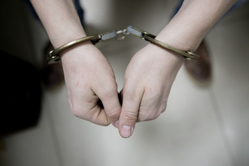The arrested criminal handcuffed. Hands with handcuffs in the front