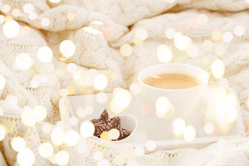 Hot beverage mug with chocolate cookies in a white wool blanket. Hot drink, cozy home and cold season concept