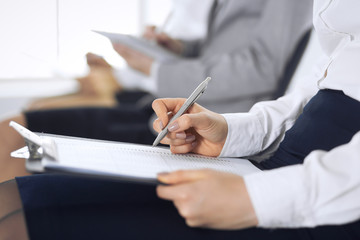 Business people taking part at conference or training at office, close-up. Women sitting on chairs and making notes like at queue or meeting 